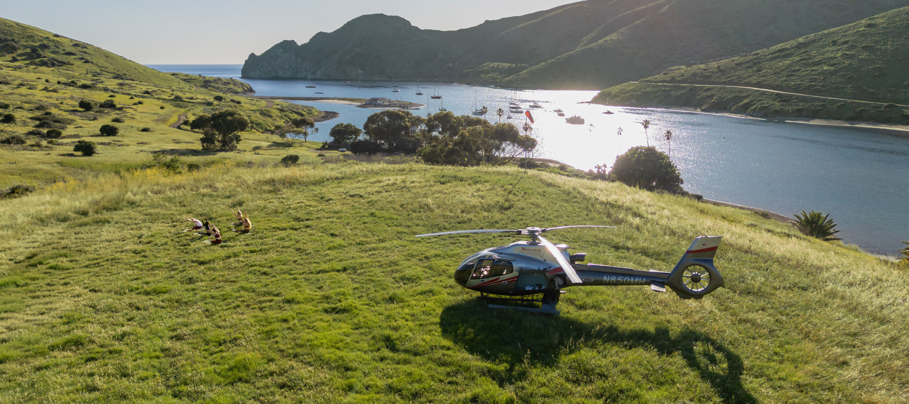 Aerial view of a helicopter landed on a grassy hillside above Two Harbors