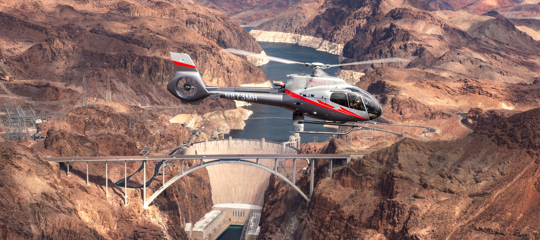 Helicopter flying over Hoover Dam in Nevada at sunset
