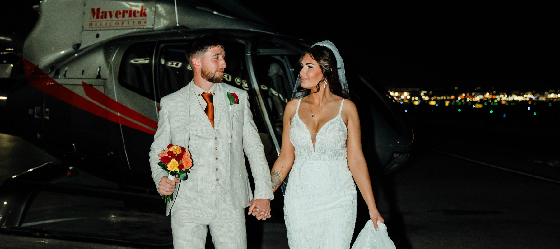 Newlyweds posing beside their Maverick helicopter after a Las Vegas Strip wedding flight