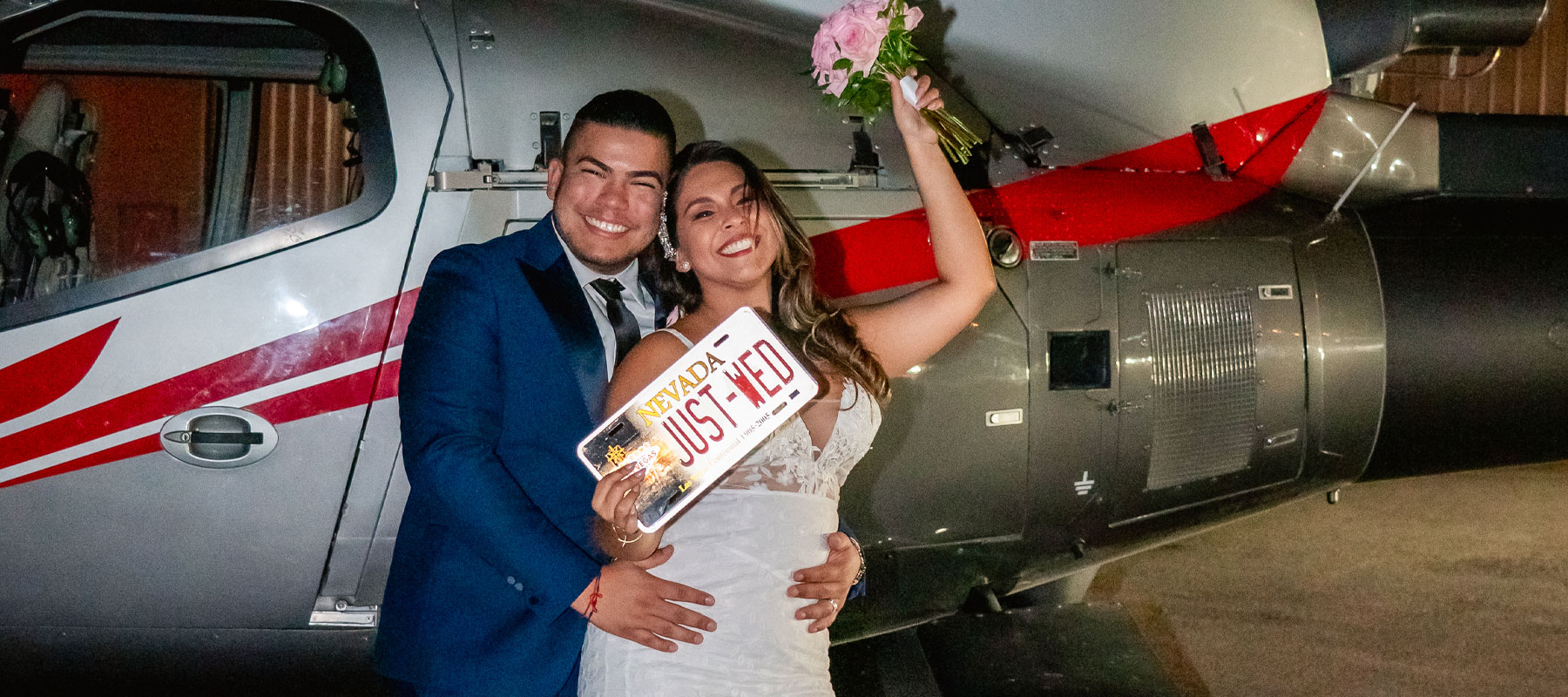 Bride and groom celebrating next to a Maverick Helicopters aircraft after their wedding ceremony